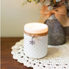 white hobnail glass jar candle with a charm on a table